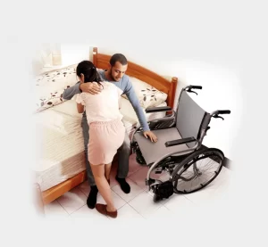 Woman assisting a man to tranfer from wheelchair to bed
