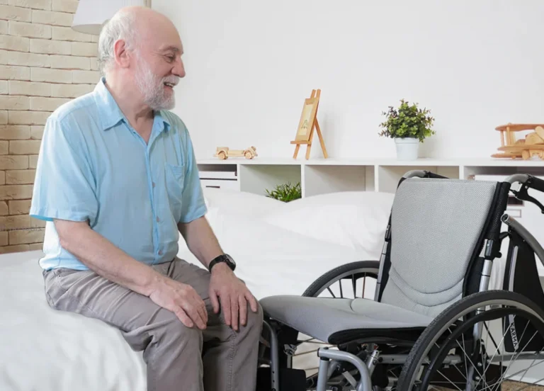 old man sitting on the bed with wheelchair near